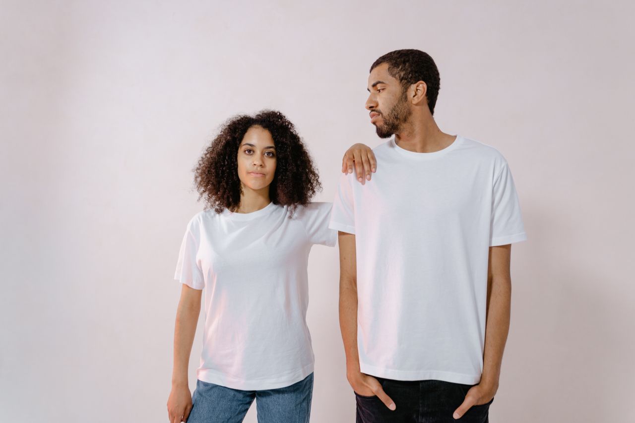 Young man and woman posing in white t-shirts in a studio. Casual and stylish look.